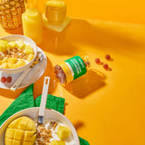Cordyceps Mushroom Gummies jar alongside a bowl of fruit and a drink, highlighting the tropical mango and pineapple flavor.