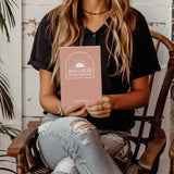 Woman holding the Wellness Remembered Mental Health Journal, showcasing mindfulness and self-improvement.