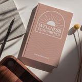 Wellness Remembered Mental Health Journal on wooden table, designed for daily mindfulness and self-improvement.